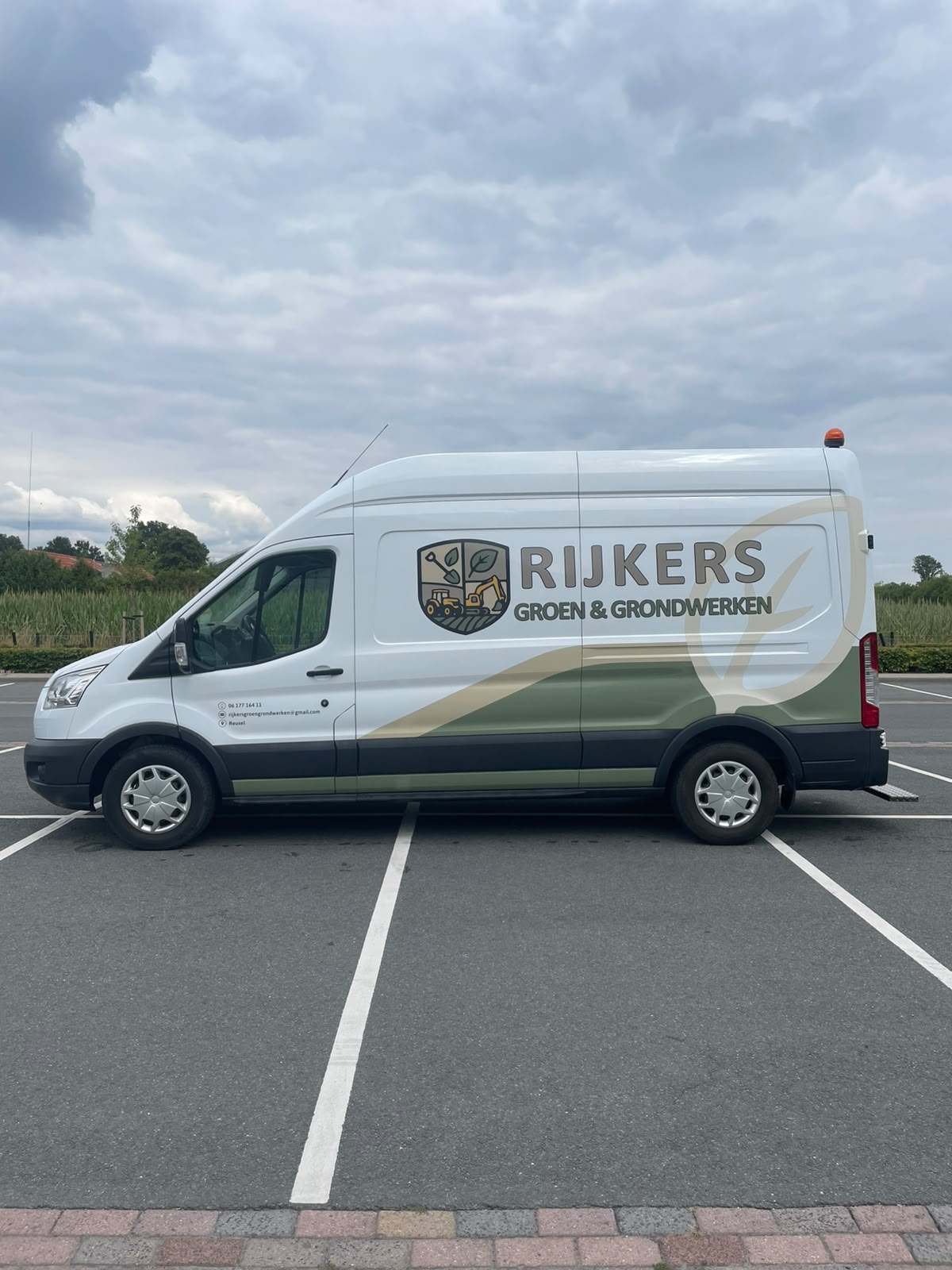Bedrijfsbus van Rijkers Groen & Grondwerken langs een veld